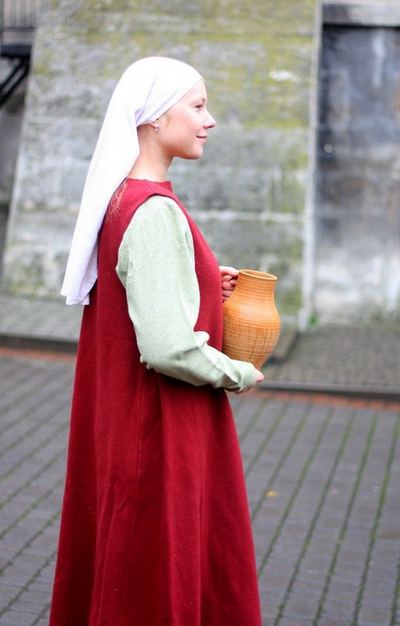 An actress in a white coif with a jug