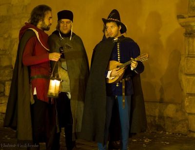 Three musicians in cloaks with a lantern and a lute